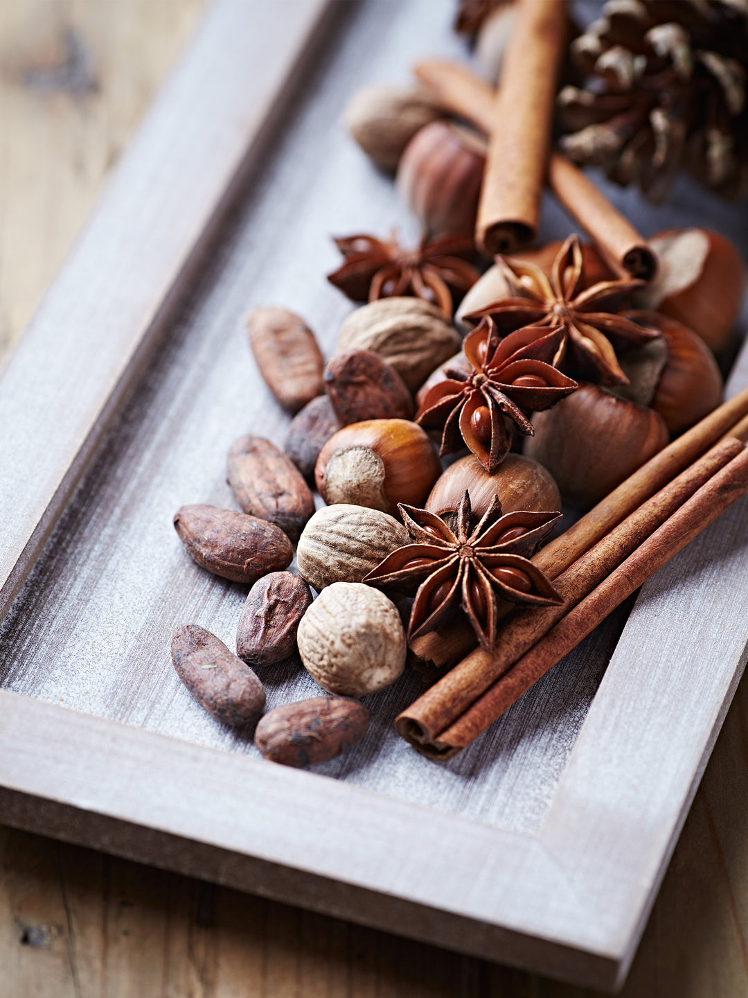 Various baking spices on a wooden tray, with nutmeg, cinnamon, and star anise. All ingredients in Cocktail Bitters.