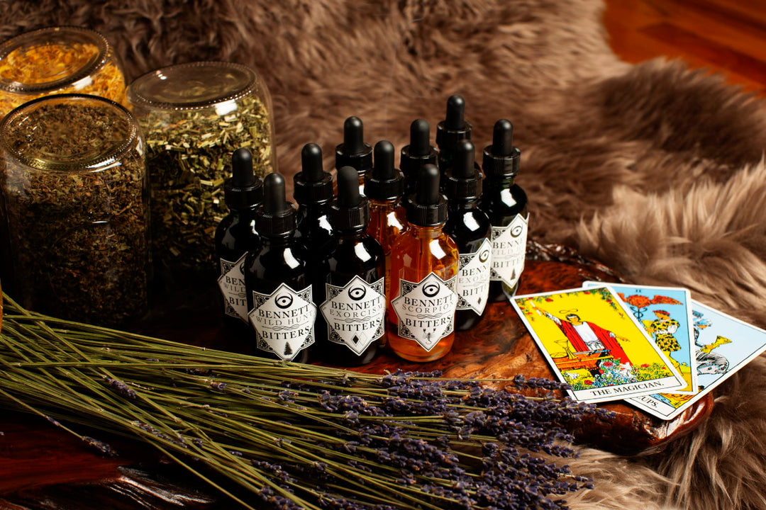 The Esoteric Collection by Bennett Biiters bottles surrounded by tarot cards, lavender, and herbs.