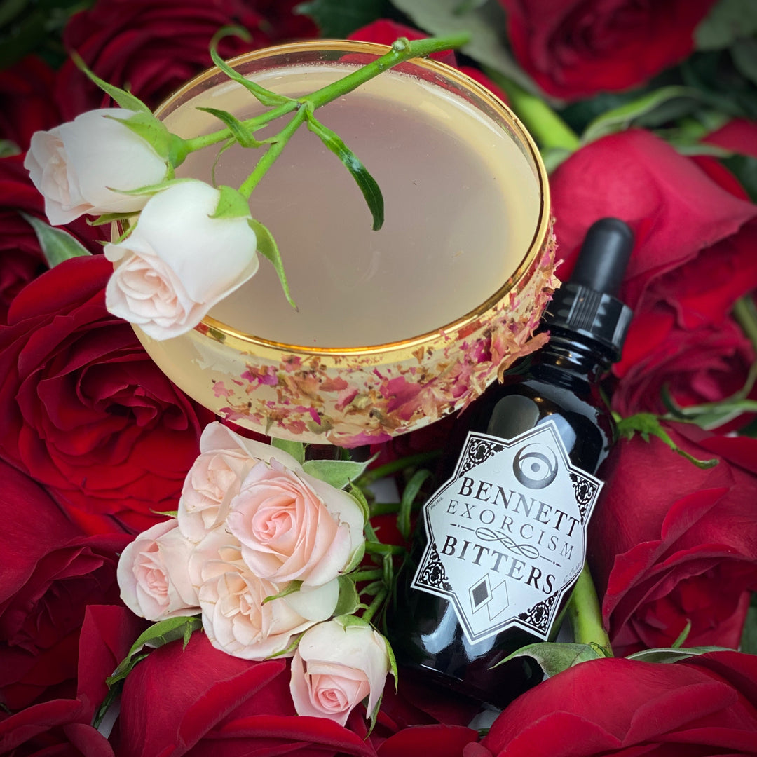 Aromatic Exorcism Bitters bottle by Bennett Bitters with a cocktail surrounded by pink and red roses.