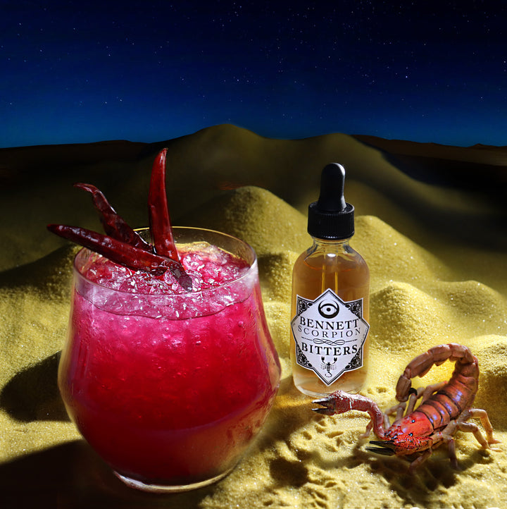 Spicy Scorpion Bitters by Bennett Bitters in a desert setting at night with a ruby red cocktail and a scorpion.