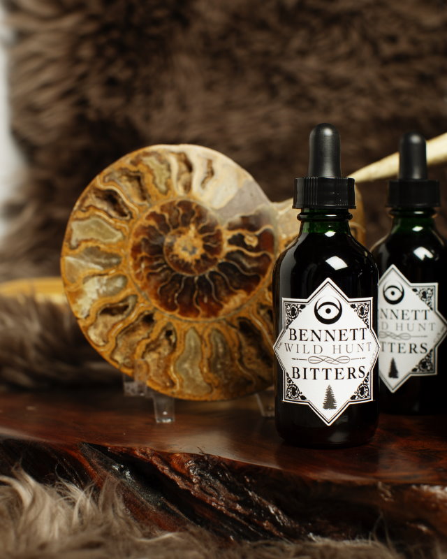 Two bottles of Herbal Wild Hunt Bitters by Bennett Bitters with a fossil.  