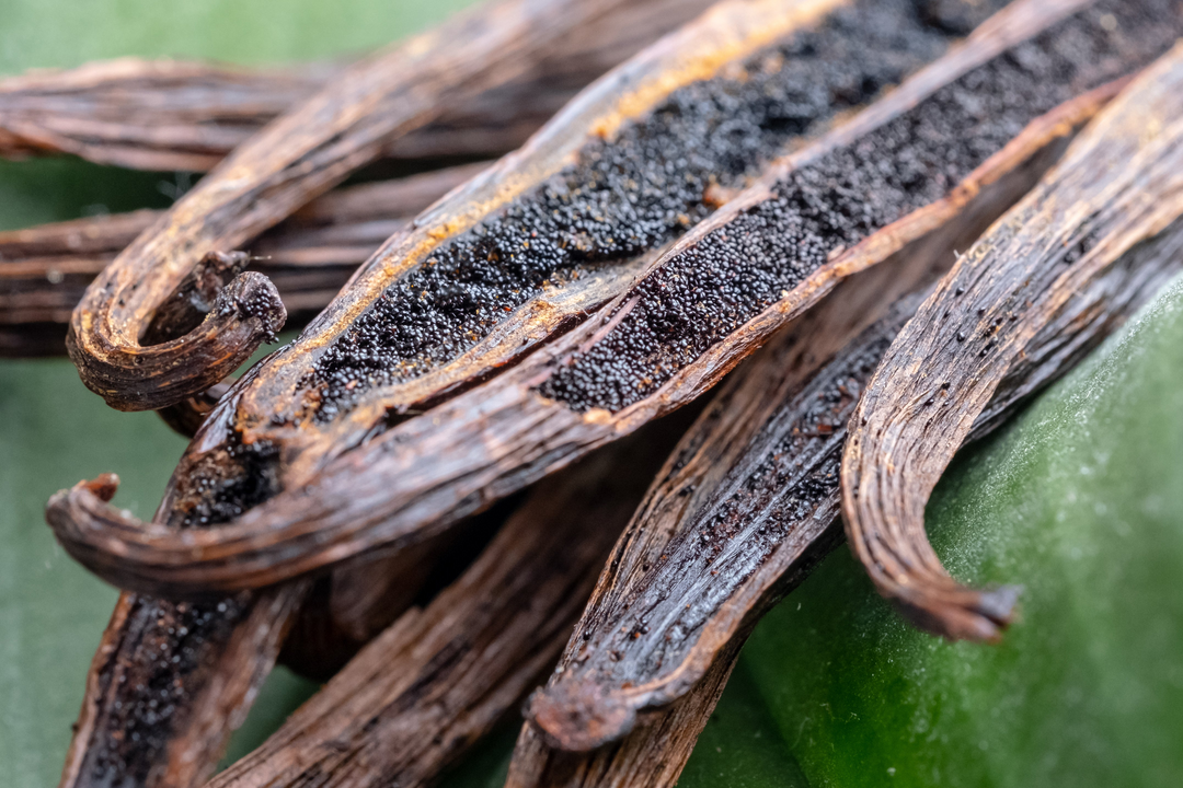 Close up image of split open vanilla bean pods with seeds in them.